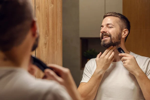 Reflejo Hombre Barbudo Afeitándose Barba Con Una Máquina Afeitar Mientras — Foto de Stock