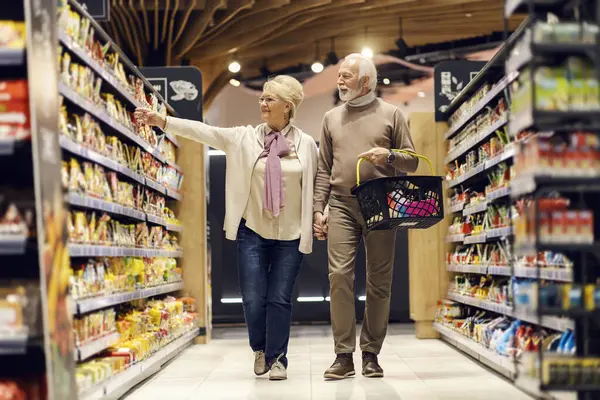 ハイパーマーケットで食料品を選んで購入する陽気なシニアカップルの全長 — ストック写真