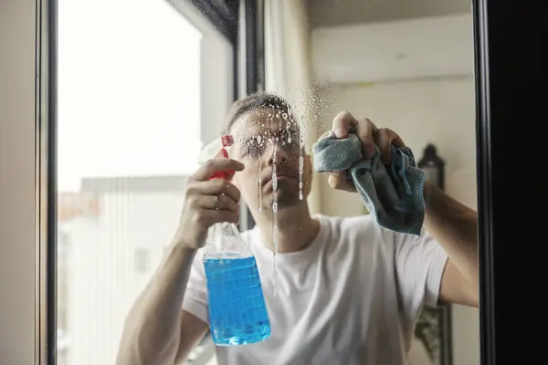 きちんとした男は 洗剤で未亡人からスタニンスポットをこすり取り除いています — ストック写真