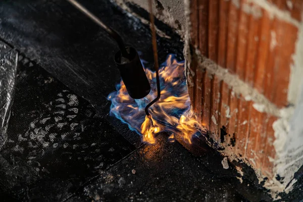 Cropped picture of a tar floor with burning tool at construction site.