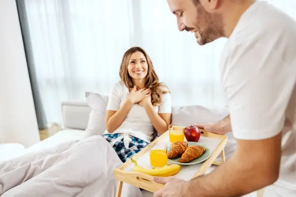一个男人在床上给他的女人端来早餐 让她大吃一惊 — 图库照片