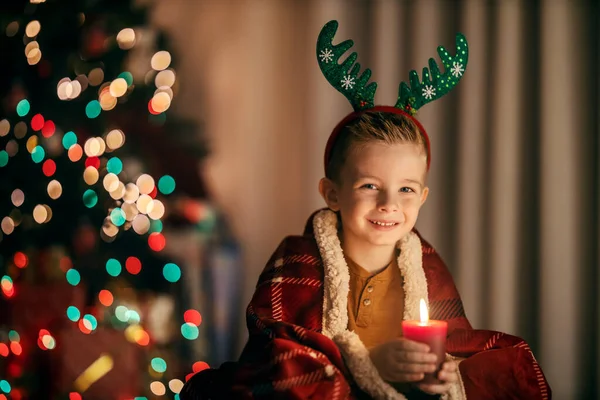 一个快乐的孩子坐在家里 在圣诞节和新年前夕举着蜡烛 对着摄像机微笑 — 图库照片