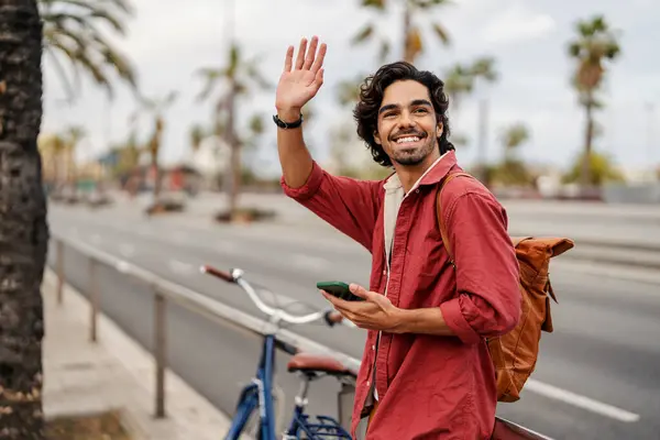 Homem Feliz Com Telefone Está Acenando Para Amigo Uma Rua Fotografias De Stock Royalty-Free