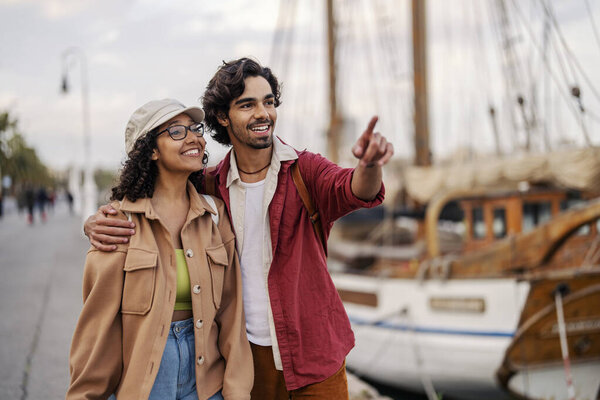 A travelers are hugging and smiling while pointing and going sightseeing on the dock in Europe. — Stock Image Travelers Hugging Smiling While Pointing Going Sightseeing Dock Europe Stock Image