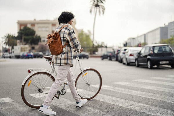 An interracial hipster is pushing his bicycle across the zebra while visiting Spain. — Stock Image Interracial Hipster Pushing His Bicycle Zebra While Visiting Spain Stock Image