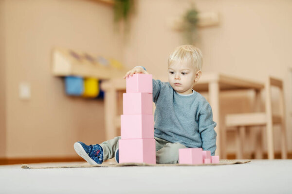 A kindergartener is playing with montessori blocks. — Stock Image Kindergartener Playing Montessori Blocks Stock Photo
