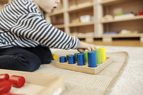 Close up of a boy ordering shapes by size and playing with montessori toy in nursery. — Stock Image Close Boy Ordering Shapes Size Playing Montessori Toy Nursery Royalty Free Stock Photos