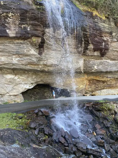 stock image Woman standing behind Bridal Veil Falls near Highlands, North Carolina in the Nantahala National Forest