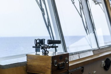 Nautical black sextant placed on wooden box in navigational bridge. Navigational equipment. Celestial navigation.