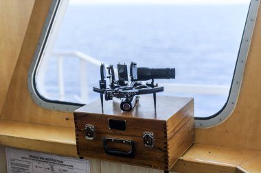 Nautical black sextant placed on wooden box in navigational bridge. Navigational equipment. Celestial navigation.