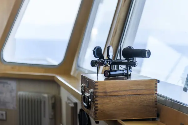 Nautical black sextant placed on wooden box in navigational bridge. Navigational equipment. Celestial navigation.
