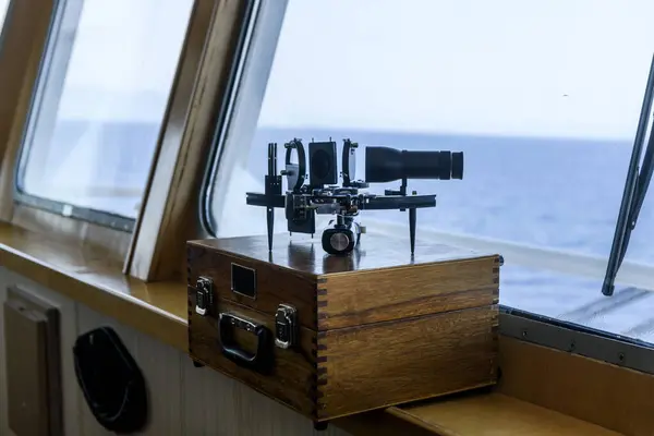 Nautical black sextant placed on wooden box in navigational bridge. Navigational equipment. Celestial navigation.