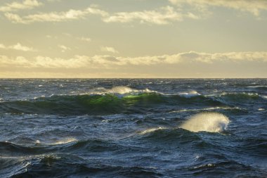 Güzel deniz manzarası. Dalgalar, bulutlar ve güzel ışıklandırmalı gökyüzü. Altın saat.