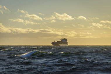 Denizde bir gemi. Güzel deniz manzarası. Dalgalar, bulutlar ve güzel ışıklandırmalı gökyüzü. Altın saat.