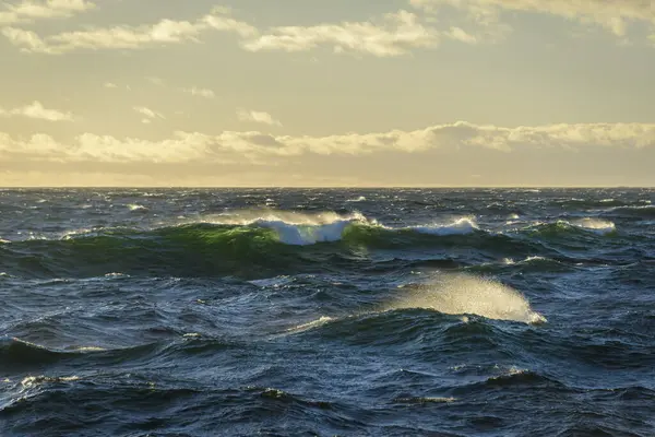 Güzel deniz manzarası. Dalgalar, bulutlar ve güzel ışıklandırmalı gökyüzü. Altın saat.