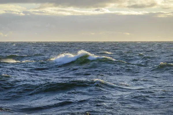 Güzel deniz manzarası. Dalgalar, bulutlar ve güzel ışıklandırmalı gökyüzü. Altın saat.