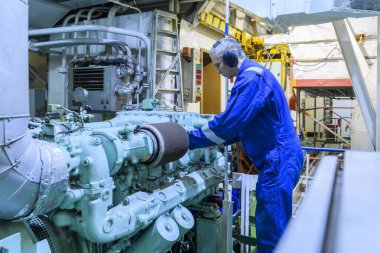 Mavili mühendis, makine dairesindeki jeneratörün bakımını yapıyor. Denizde çalışmak. Motorcu.