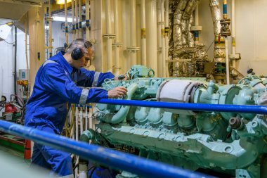 Mavili mühendis, makine dairesindeki jeneratörün bakımını yapıyor. Denizde çalışmak. Motorcu.