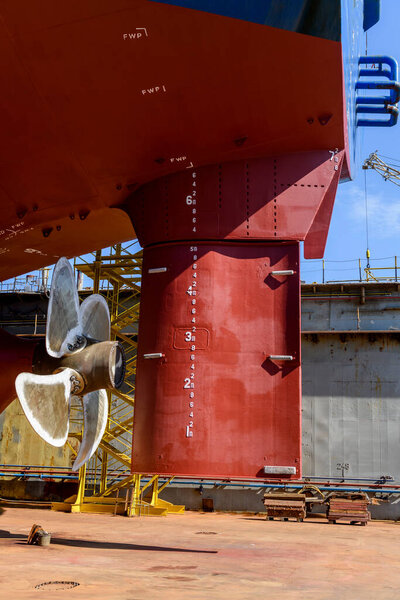 Cargo vessel in dry dock on ship repairing yard. Variable pitch propeller and rudder.