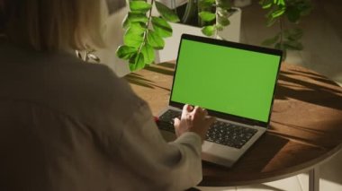 Kadın Giriş Anahtarı 'na, Laptop Yeşil Ekran Krom Anahtarı' na basın. Ağır çekimde bilgisayar modeli kullanan, tanımlanamayan beyaz bir kadının omuz üstünden çekilen fotoğrafı.