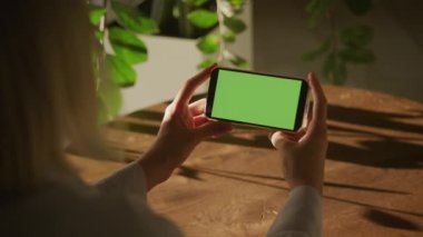 Yeşil Ekran Akıllı Telefonu. Chroma Key Smart Phone izliyordum. Tanımlanamayan beyaz kadın elinde bir telefonun yatay maketini tutuyor ve ağır çekimde el kamerasının etrafında dönüyor.