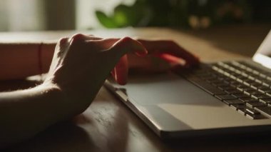 Hand scrolling on laptop touchpad. Browsing online close up. Caucasian woman arm swipe on computer in sunset sunlight in slow motion