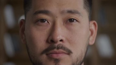 Extreme close up of an Asian man opening eyes in slow motion indoors