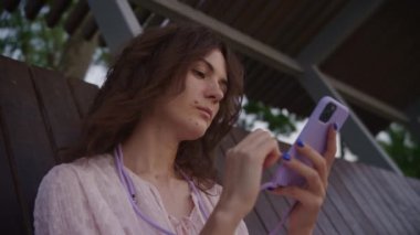 Young woman browsing on a smartphone in the park outside in slow motion
