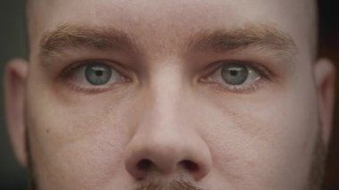 Blue eyes looking at camera then left and right. Extreme close up of caucasian man eyes in a gesture in slow motion