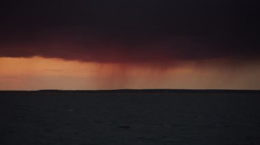Distant rain over a stormy river view. Moody scenic sunset panorama