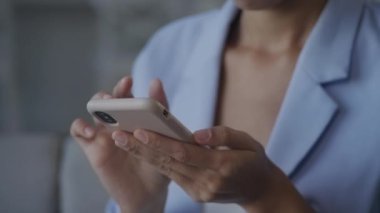Woman browsing on smartphone extreme close up. Camera moving from hands holding a smart phone to a face of an African American female looking focused