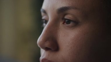 Woman eyes open in slow motion in side view indoors. African American female face extreme close up