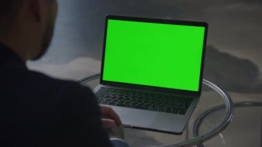 İş adamı yeşil ekran krom anahtarı olan dizüstü bilgisayarı ağır çekimde izliyor.
