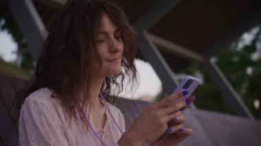 Akıllı telefondan mesaj atan genç bir kadın. Kıvırcık beyaz kadın telefonuna yavaş çekimde bir mesaj yazıyor.