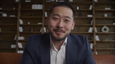 POV İşadamı video konferansında yavaş çekimde konuşuyor. İnternetteki görüntüde, takım elbiseli Asyalı bir adam dizüstü bilgisayarlı bir fotoğraf makinesinde konuşuyor.