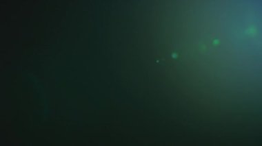 Lens flare of a cinema zoom optics on black background shot in slow motion with green and blue coating
