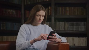 Genç bir kadın internette akıllı telefondan kitap okuyor. Göz gezdirirken beyaz kadın yüz ifadesi