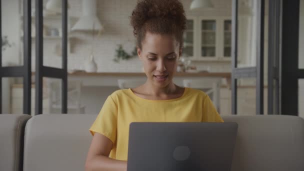 遅い動きでラップトップで屋内で働く女性 ロフトのアパートのノートパソコンで働いている若い大人のアフリカ系アメリカ人のビジネスマンの閉鎖スローモーションでハンドヘルド — ストック動画