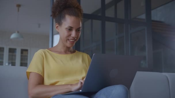 笑顔でノートパソコンで働く女性 若いアフリカ系アメリカ人女性のコンピュータ室内で入力 低角度ショット — ストック動画
