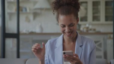 Woman getting promotion, Businesswoman achievement. African American adult female receiving great news on her smartphone indoors in slow motion