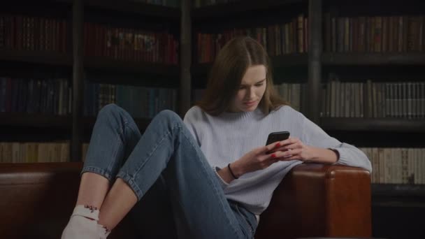 Jonge Vrouw Browsen Online Met Behulp Van Smart Phone Binnen — Stockvideo