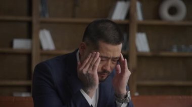 Businessman feeling headache, man with pain in head in office