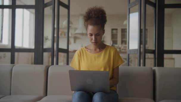 女性はノートパソコンで働いていて 起業家は疑います アフリカ系アメリカ人女性がコンピュータ上でオンラインで閲覧 — ストック動画