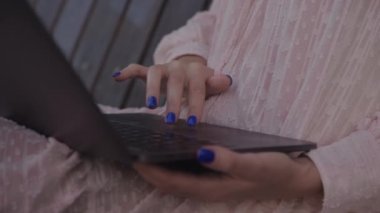 Hand scrolling on a laptop touchpad in park. Caucasian female hand browsing on computer outside