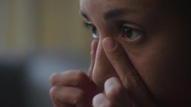 Woman touching her nose and eyes close up in slow motion, African American female face side view
