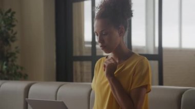Woman considering a decision. Thoughtful customer. African American female shopping online on her laptop indoors