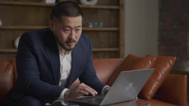 Man searching a job offer online using laptop. Businessman browsing on computer showing emotions