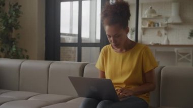 Woman using laptop in positive mood, African American female browsing online on computer
