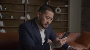 Mali piyasadaki çöküşle ilgili haberleri okuyan üzgün bir adam. Yetişkin Asyalı işadamının etrafında dönüp akıllı telefondan kötü haberler alıyor.