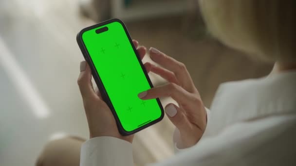 緑色の画面スマートフォンで手スクロール 肩のビュー上 Fpsで屋内にクロマキー付きスマートフォンを使用する女性 — ストック動画